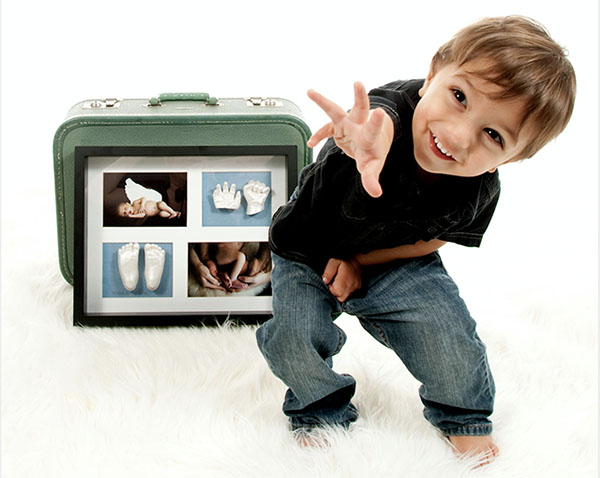 Little boy showing off with the hand and feet Memory Castings Sculptures he made as a baby