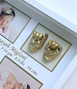 Little girl sitting in her backyard with the little feet Memory Castings Shadowbox she made as a newborn baby
